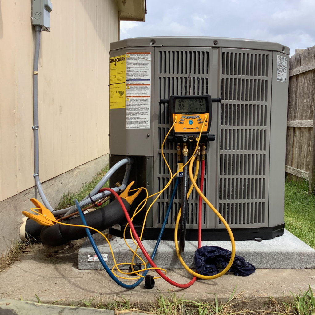 Refrigerant gauges hooked up to a home air conditioning condenser during an E+M diagnostic